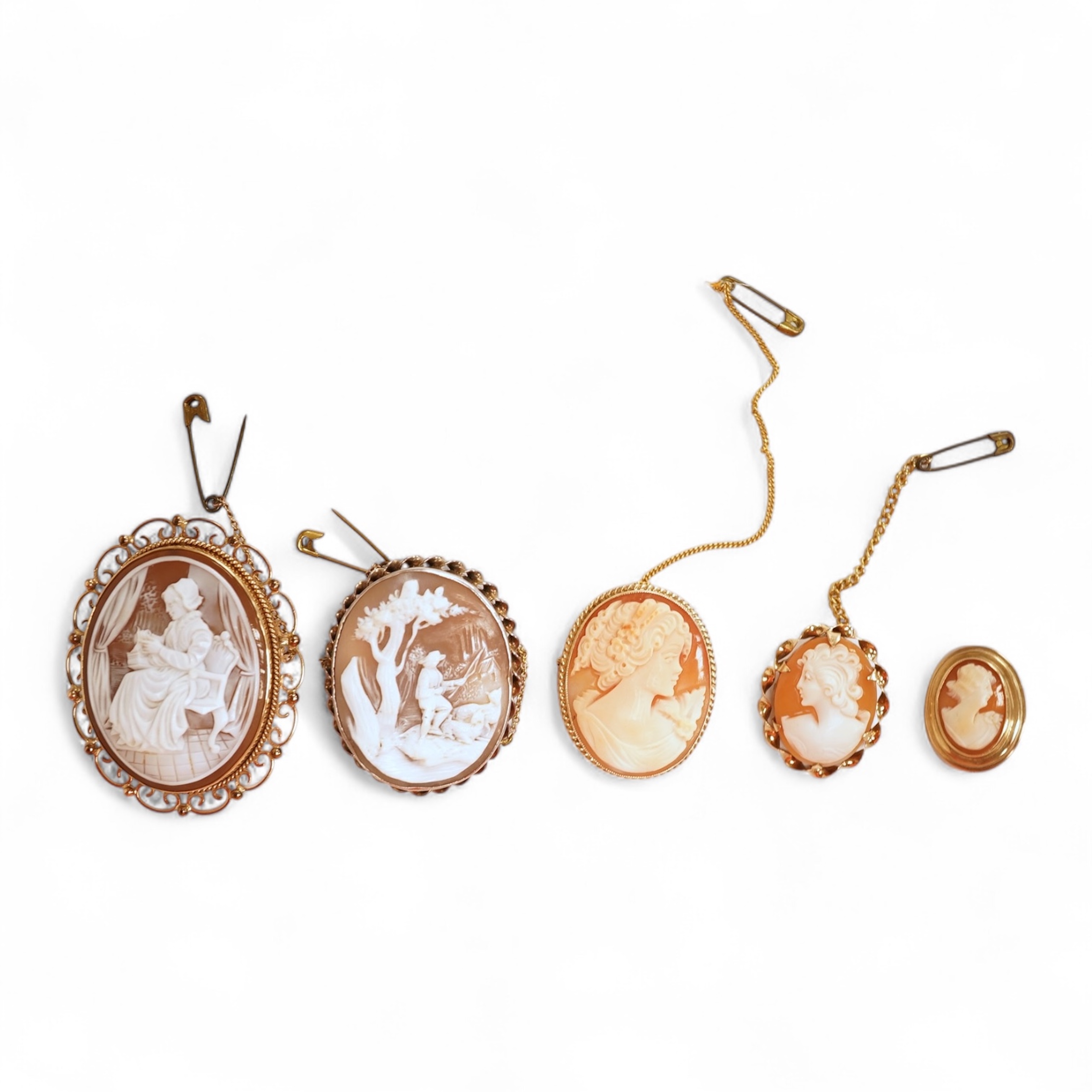 A collection of five cameo brooches, each of oval outline, set with a carved shell cameo, variously depicting three women in profile, a seated lady doing needlework, and a pastoral scene of a shepherd, longest 6.8cm, thr